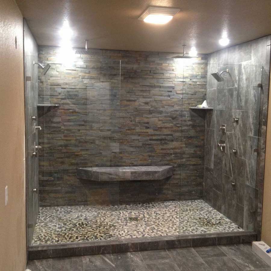 Spa-style luxury shower featuring natural stone accent wall, built-in bench seating, and premium shower systems